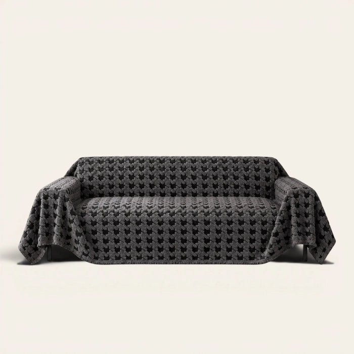 Charcoal Gray Cozy Houndstooth sofa throw draped over a three seater sofa, front view on ivory background