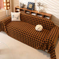 Overhead view of Coffee Brown Cozy Houndstooth throw on a sofa with cushion and knot ball beside wood shelving