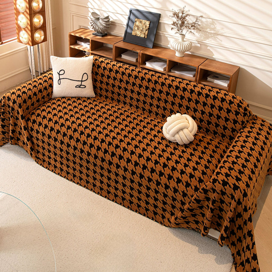 Overhead view of Coffee Brown Cozy Houndstooth throw on a sofa with cushion and knot ball beside wood shelving