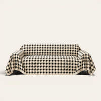Cozy Houndstooth sofa throw in Ivory Black draped over a couch, front view on ivory background