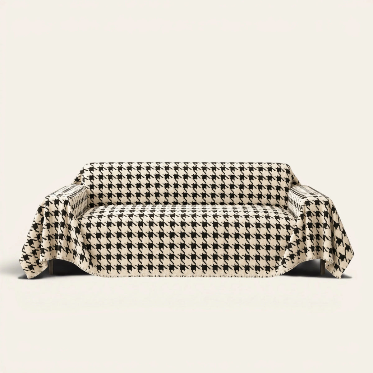 Cozy Houndstooth sofa throw in Ivory Black draped over a couch, front view on ivory background
