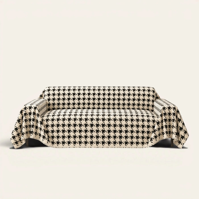 Cozy Houndstooth sofa throw in Ivory Black draped over a couch, front view on ivory background