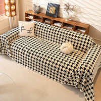 Cozy Houndstooth throw in Ivory Black over a sofa with pillows, angle with styled shelf