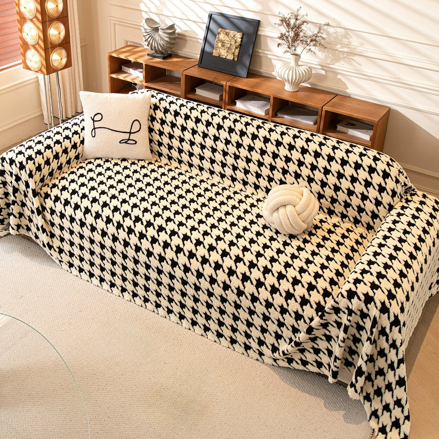 Cozy Houndstooth throw in Ivory Black over a sofa with pillows, angle with styled shelf