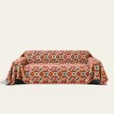 Scarlett Nomad Crimson Boho kilim throw draped over a two-seat sofa on ivory background