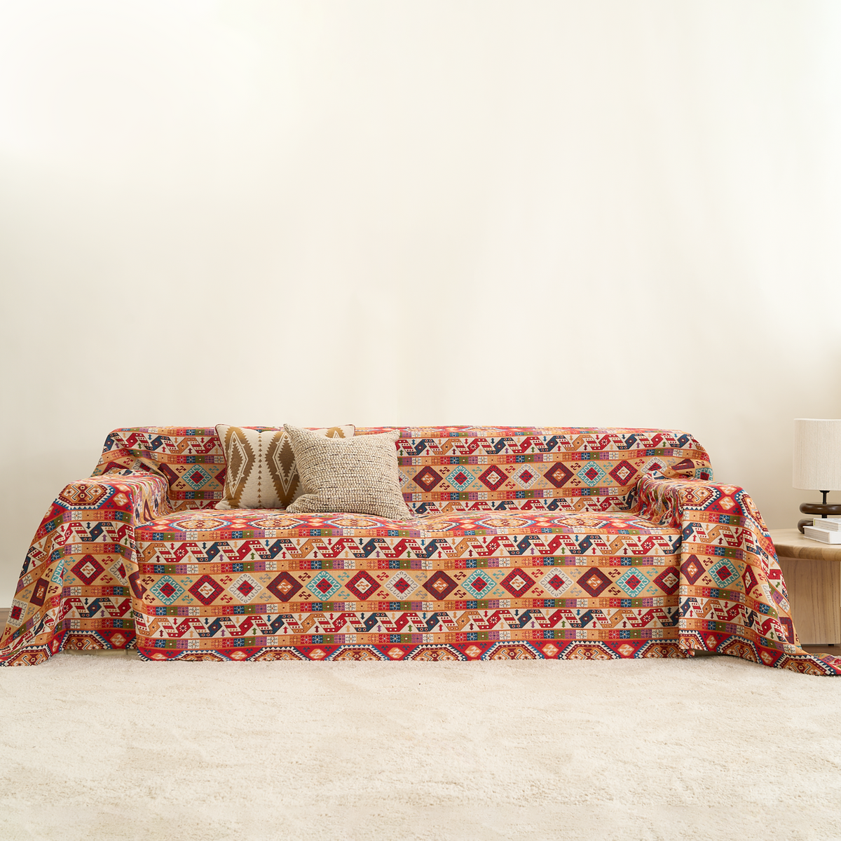Colorful crimson boho throw covering a sofa with knit cushion and lamp in a warm room