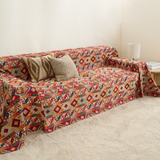 Crimson boho kilim throw on a sofa with layered cushions, lamp and book