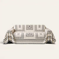 Fringed Boho sofa throw in Ivory Ink draped over a couch, front view on ivory background