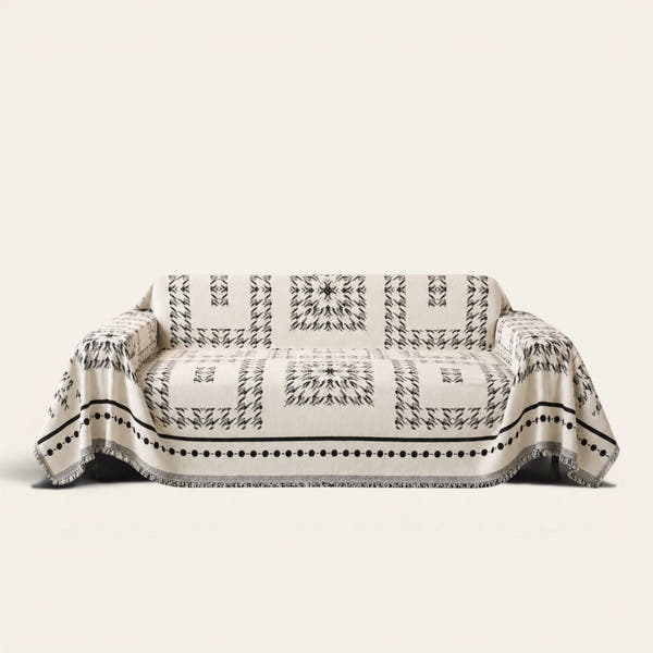 Fringed Boho sofa throw in Ivory Ink draped over a couch, front view on ivory background