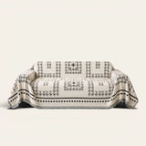 Fringed Boho sofa throw in Ivory Ink draped over a couch, front view on ivory background