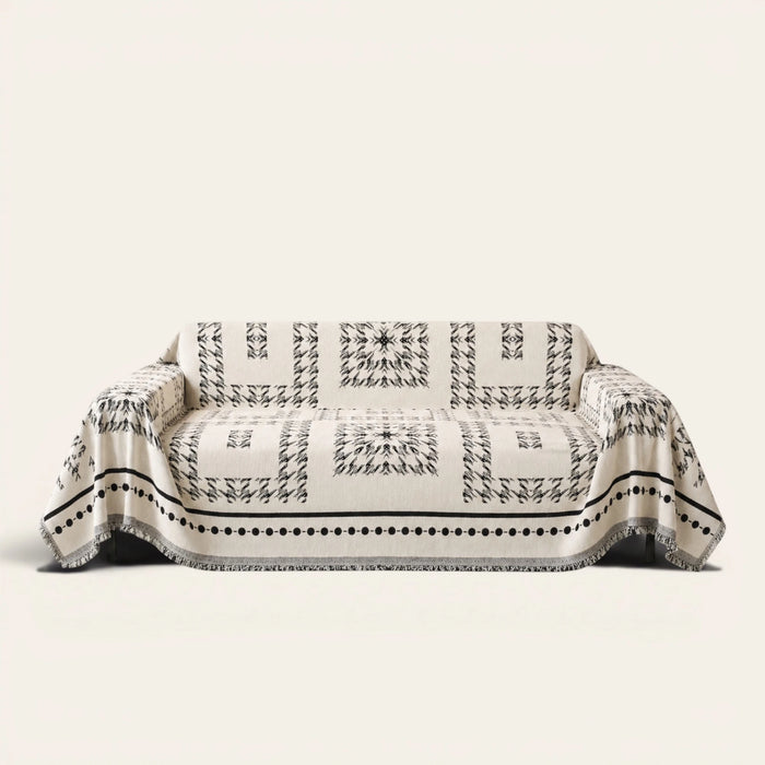 Fringed Boho sofa throw in Ivory Ink draped over a couch, front view on ivory background