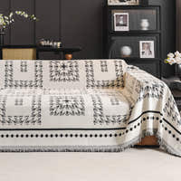 Ivory Ink Fringed Boho throw over a sofa in a dark styled room with black shelving