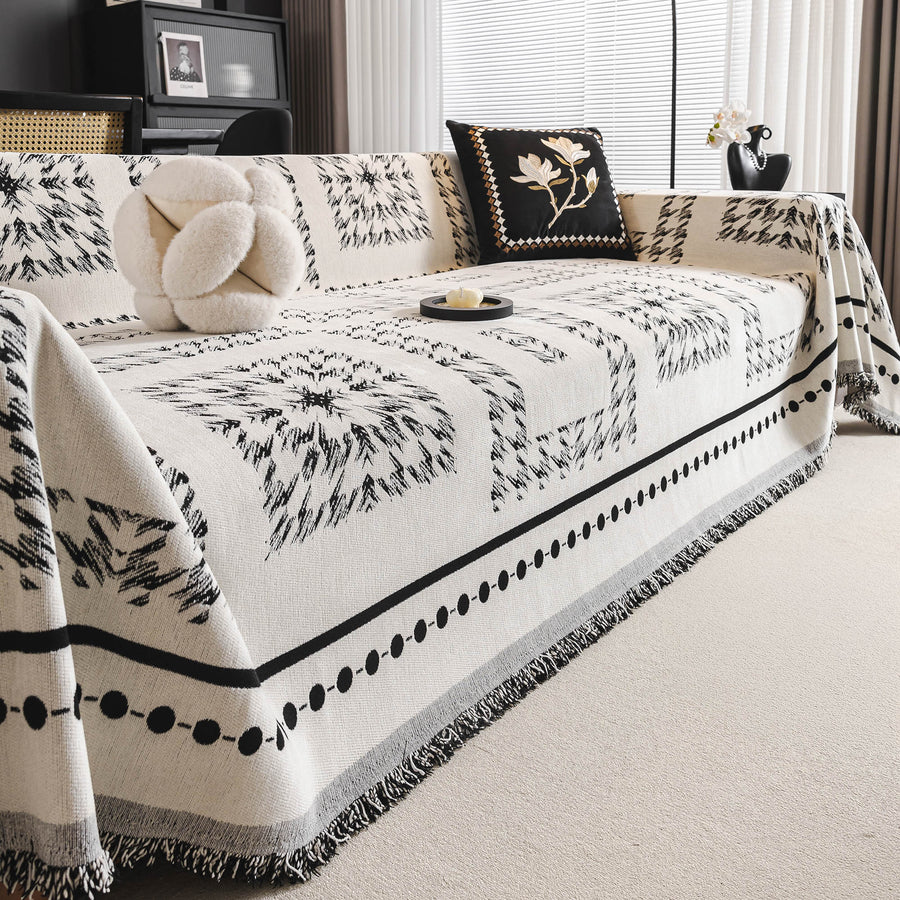 Ivory Ink Fringed Boho throw on a sofa with a fluffy cushion and floral pillow, angle view