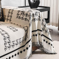 Close-up of the Ivory Ink throw draped over a sofa arm with beaded stripe border and fringe