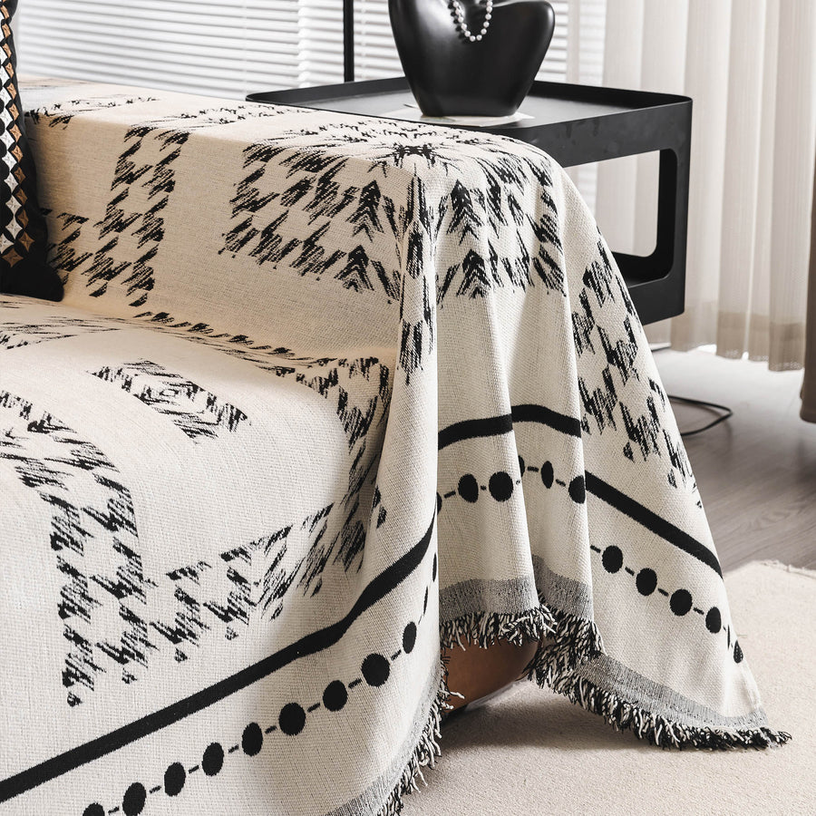 Close-up of the Ivory Ink throw draped over a sofa arm with beaded stripe border and fringe