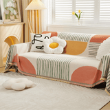 Citrus Burst Fruitopia throw over a sofa with line-art and daisy cushions, angled view with tulips and wood cabinet