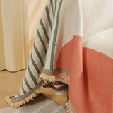 Close-up of Citrus Burst Fruitopia throw cascading over the sofa corner with coral blocks and colorful tasseled fringe
