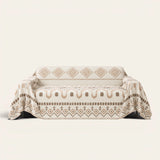 Geometric Boho sofa throw in Beige Geometry draped over a couch, front view with aztec diamonds and fringe