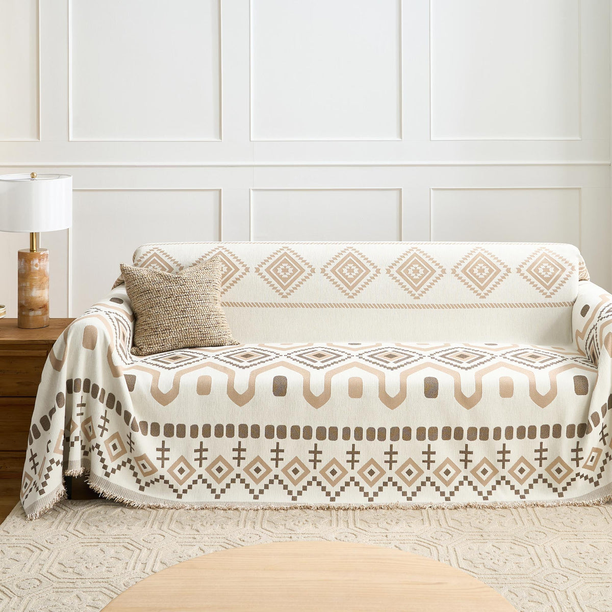 Beige Geometry Geometric Boho throw styled on a sofa against a paneled wall with a lamp and cushion