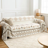 Angled view of the Beige Geometry boho throw over a sofa beside a wood table and woven rug
