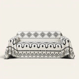 Geometric Boho sofa throw in Black Geometry over a couch, front view with monochrome aztec pattern and fringe