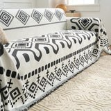 Angled view of the Black Geometry throw draped on a sofa beside a window and wood side table