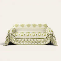 Geometric Boho sofa throw in Green Geometry draped over a couch, front view on ivory background