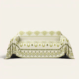Geometric Boho sofa throw in Green Geometry draped over a couch, front view on ivory background