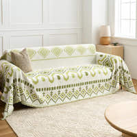 Geometric Boho throw in Green Geometry over a sofa, side angle with woven rug and window light