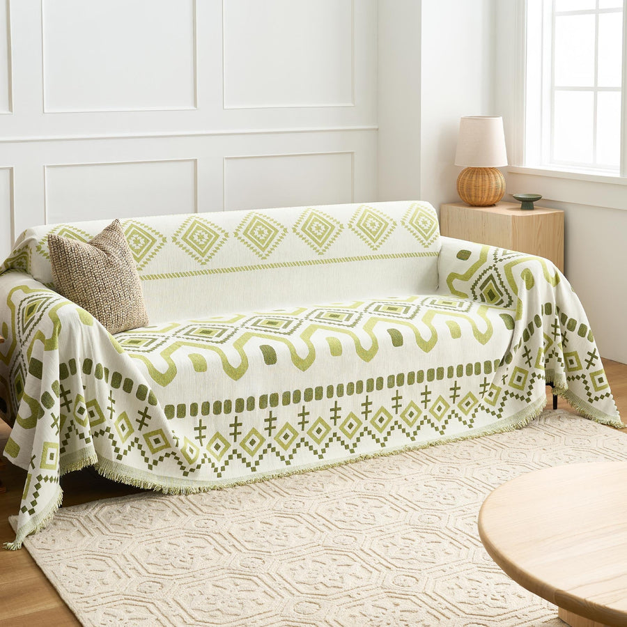 Geometric Boho throw in Green Geometry over a sofa, side angle with woven rug and window light