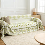 Geometric Boho throw in Green Geometry over a sofa, side angle with woven rug and window light