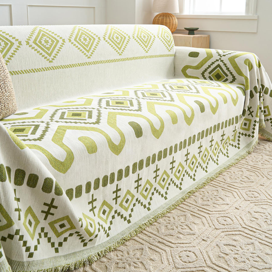 Green Geometry Geometric Boho throw draped over a sofa arm and seat, three-quarter view with fringe