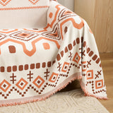 Close-up of the orange and brown boho throw draped over a sofa corner near a rug