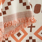 Detail of the fringed edge and textured weave of the orange geometric boho throw