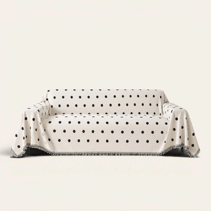 Geometric Chenille sofa throw in Black Boba over a couch, front view with black polka dots and fringe