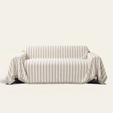 Geometric Chenille sofa throw in Black Linearity over a couch, front view with thin vertical stripes and fringe