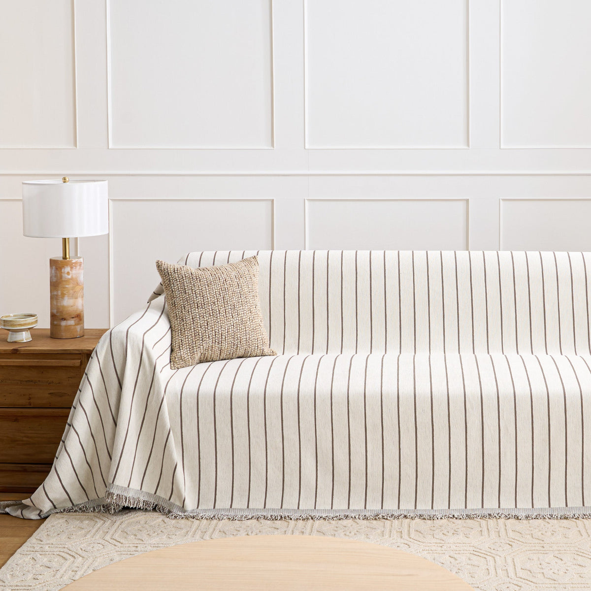 Black Linearity striped throw styled on a sofa against a paneled wall with a knit cushion and lamp