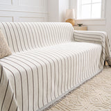Angled view of the Black Linearity throw on a sofa by a window, showing its reversible taupe side