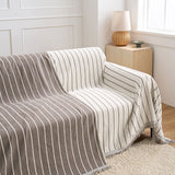Black Linearity throw draped over a couch revealing the brown reversible stripe backing beside a rattan lamp