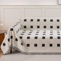 Checkered Onyx Geometric Chenille throw on a sofa with a black square grid pattern beside a side table