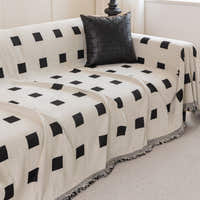 Checkered Onyx Geometric Chenille throw over a corner sofa with a woven black cushion