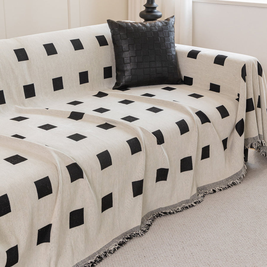 Checkered Onyx Geometric Chenille throw over a corner sofa with a woven black cushion