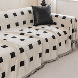 Checkered Onyx Geometric Chenille throw over a corner sofa with a woven black cushion