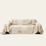 Brown Stream Geometric Harmony sofa throw draped over a three seater sofa, front view on ivory background with fringed hem