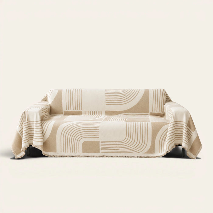 Brown Stream Geometric Harmony sofa throw draped over a three seater sofa, front view on ivory background with fringed hem