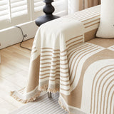 Close-up of Brown Stream Geometric Harmony throw cascading over the sofa arm with tasseled fringe by a shuttered window
