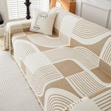 Brown Stream Geometric Harmony throw seen from above on a sofa, arcs and blocks pattern with cream cushion