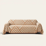 Orange Arrow geometric rust chevron sofa throw draped over a two-seat couch, front view on ivory background