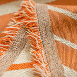 Close-up of the woven orange and cream chevron fabric with fringed edge detail