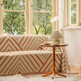 Geometric rust chevron throw styled on a couch in a sunny living room with wooden side table